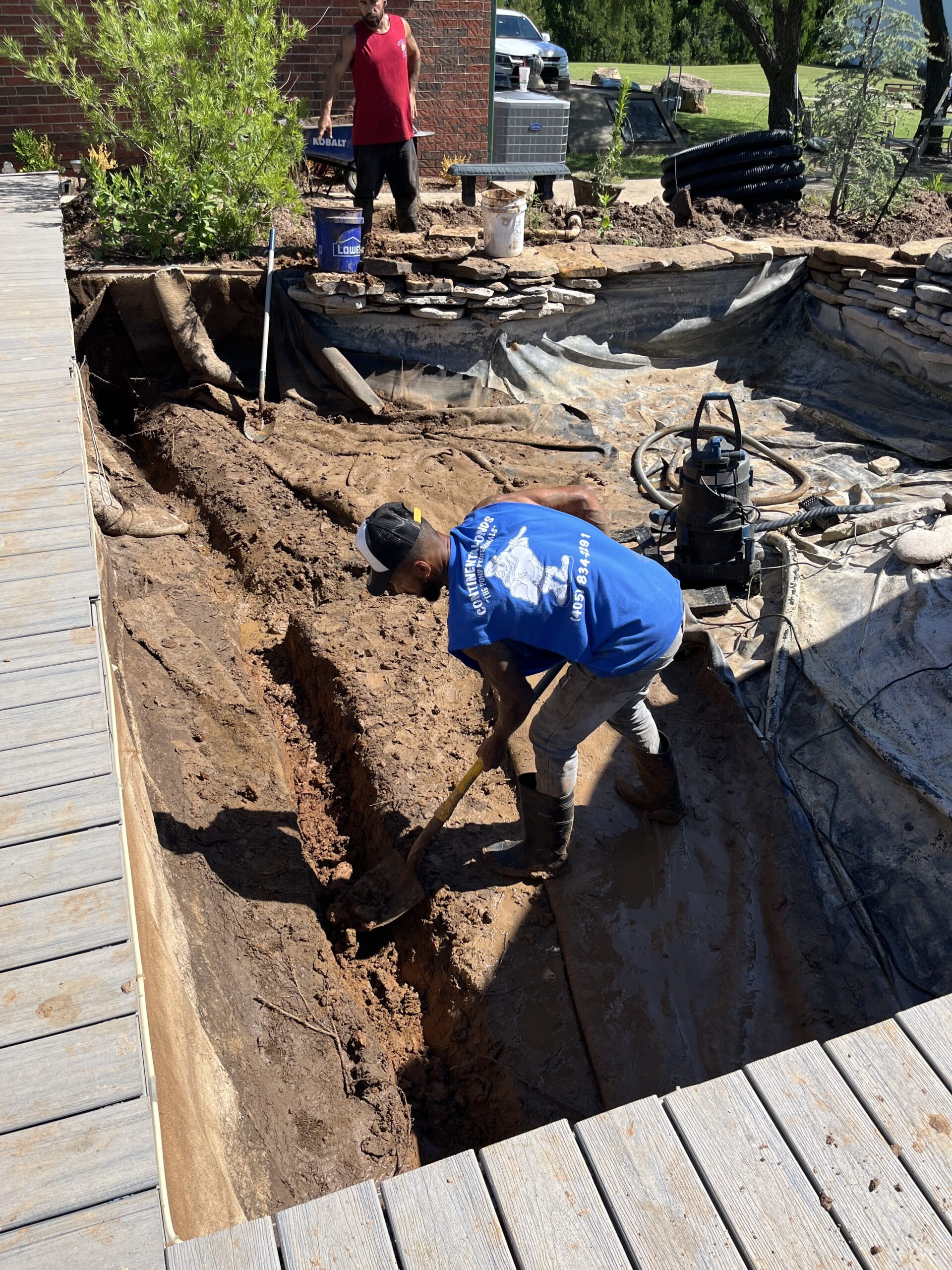 Specialist shaping pond basin and filtration layout with precise landscape construction tools