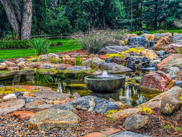 Experienced pond contractor using advanced tools to test water clarity and filtration in a completed Piedmont, OK landscape pond