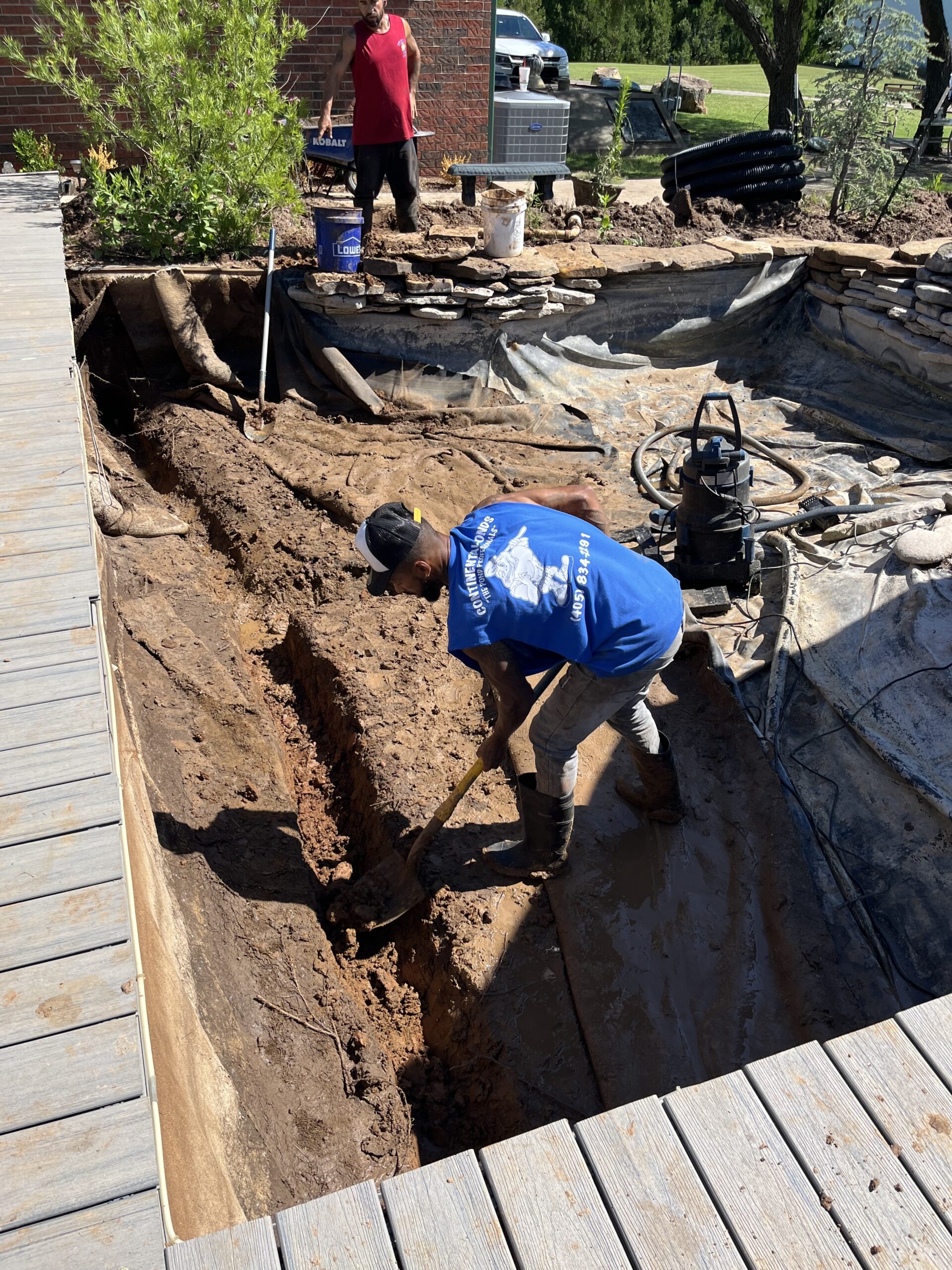 Technician performing Pond Maintenance at a Mustang, OK residential water feature while checking filtration and water movement