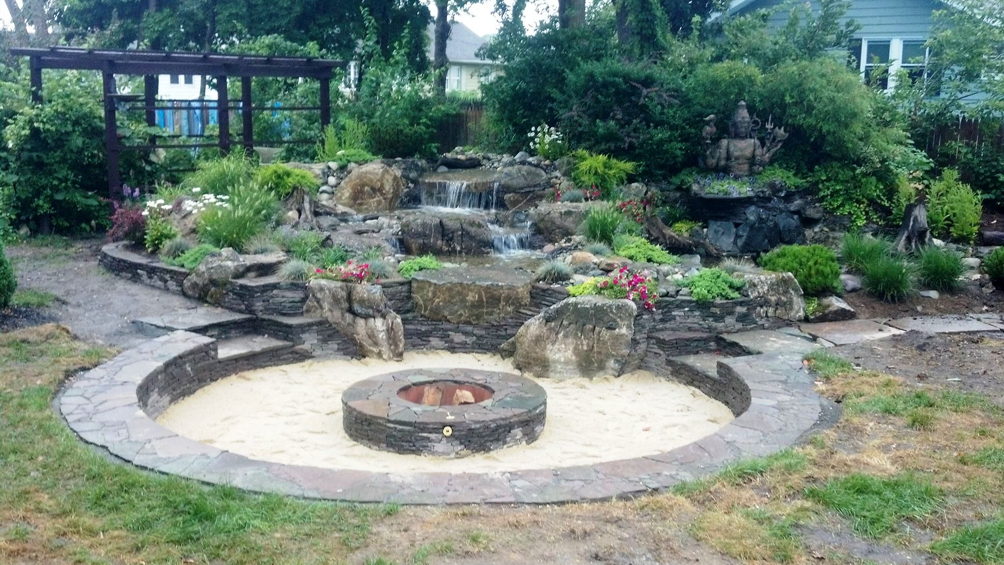 Custom backyard pondless waterfall with natural stone and landscaping in Oklahoma City