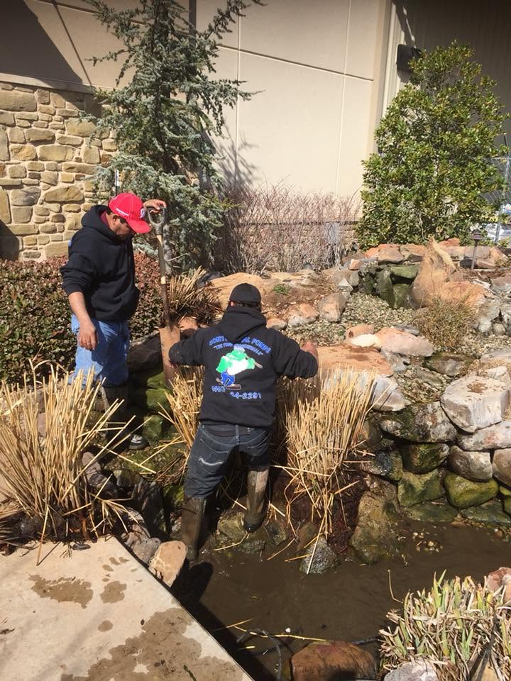 Pond repair technician troubleshooting water loss in an Edmond Oklahoma backyard pond