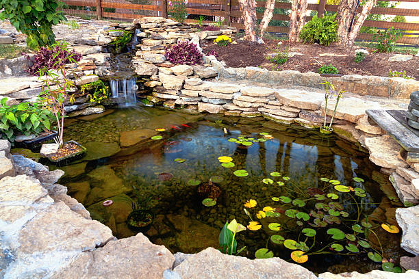 Landscape specialist adjusting water features beside a garden path in Noble, OK during a backyard installation